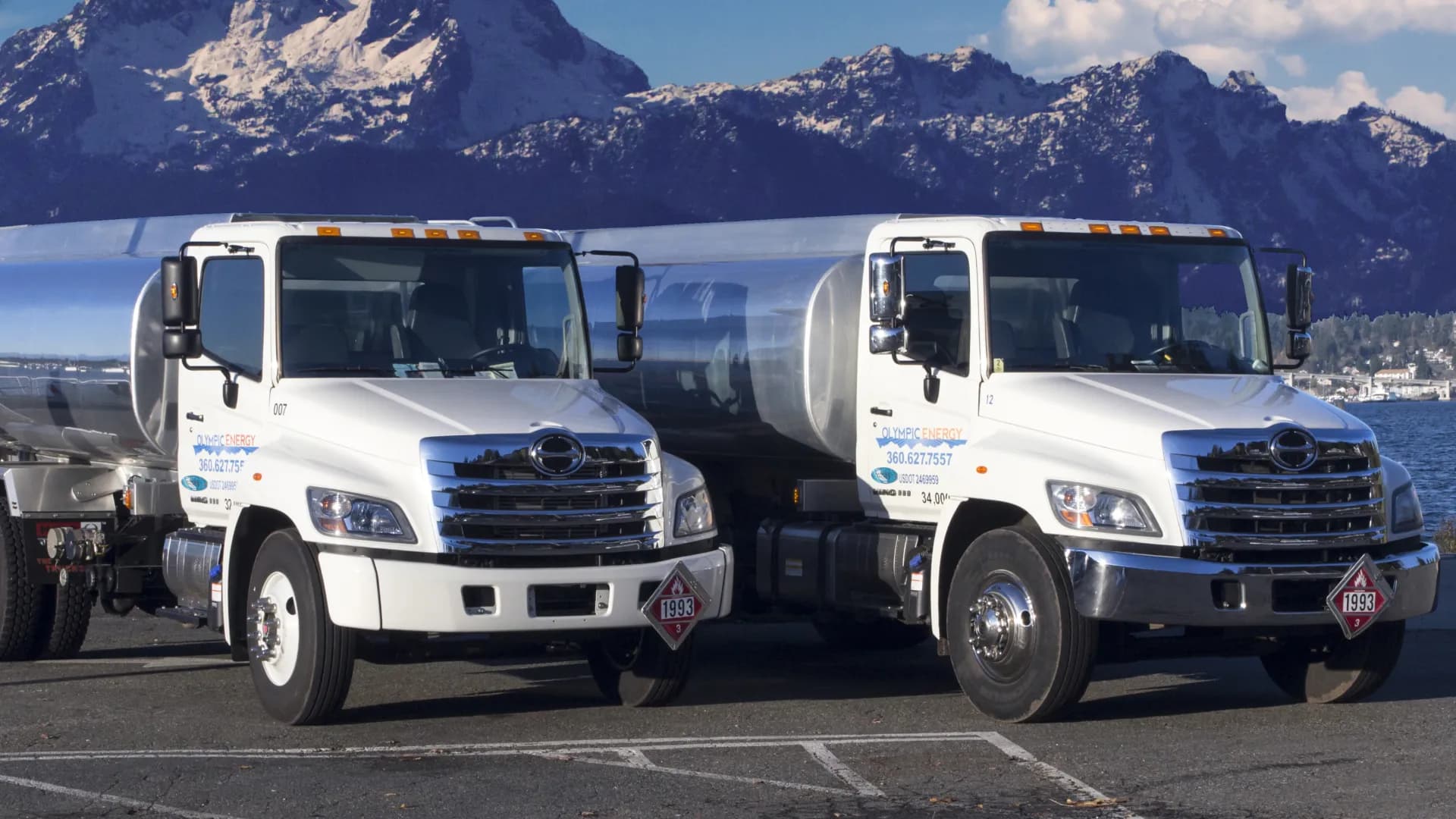 Olympic Energy delivery trucks with the Olympic mountains behind them